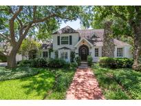 Charming two-story home with a brick walkway, mature trees and a stone chimney at 560 Bosphorous Ave, Tampa, FL 33606