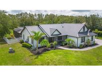 Beautiful white home featuring a metal roof and lush landscaping at 7725 235Th E St, Myakka City, FL 34251