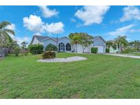 Landscaped home featuring lush green lawn, stone garden, mature trees, and charming curb appeal at 832 Birdie Way, Apollo Beach, FL 33572
