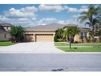 Inviting single-story home with a three-car garage, a well-manicured lawn, and lush landscaping at 10513 Palm Cove Ave, Tampa, FL 33647