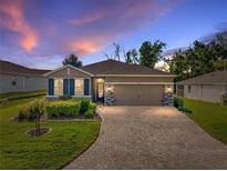 Charming single-story home featuring a brick driveway, stone accents, well-manicured lawn, and pleasant landscaping at 12492 Eastpointe Dr, Dade City, FL 33525