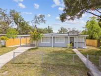 Charming single-story home with a covered carport and a well-maintained front yard and modern gray paint at 1905 E Broad St, Tampa, FL 33610