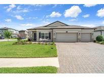 Charming home featuring a well-manicured lawn, three-car garage, and inviting front patio at 20108 Stone Pine Cir, Lutz, FL 33558