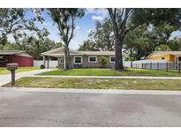 Charming one-story home featuring a well-maintained lawn and a cozy carport area with outdoor seating at 2044 Balfour Cir, Tampa, FL 33619