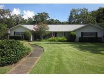 Charming single-story home with a lush lawn, mature trees, and a welcoming walkway leading to the front door at 2143 Wrens Way, Clearwater, FL 33764