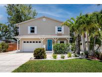 Inviting two-story home with blue door, well-maintained landscaping and attached garage at 350 Kentucky Ave, Crystal Beach, FL 34681