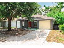 Charming home with a red front door, grey exterior, and a one-car garage with concrete driveway at 3632 E Comanche Ave, Tampa, FL 33610