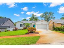 Charming single-story home with well-manicured lawn, a vibrant turquoise door and an attached garage at 859 Harbor Hill Dr, Safety Harbor, FL 34695