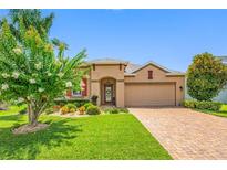 Charming single-story home with a well-manicured lawn, colorful landscaping, and a brick-paved driveway at 1242 Windy Bay Shl, Tarpon Springs, FL 34689