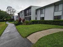 Well-maintained condo building with lush landscaping and walking path leading to the entrance at 1281 Pine Ridge E Cir # B1, Tarpon Springs, FL 34688