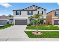 Two-story home with a well-manicured lawn, grey paint, black shutters, and a two-car garage at 12835 Wildflower Meadow Dr, Riverview, FL 33579