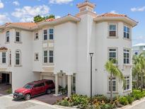 Beautiful exterior view of a three-story Mediterranean style townhome, featuring a garage and red SUV at 1340 Bayshore Blvd # 502, Dunedin, FL 34698