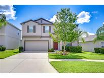 Charming two-story home with a well-manicured lawn, landscaping, and a two-car garage at 208 English Heritage Pl, Dover, FL 33527
