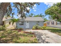 Charming single-story home with gray exterior paint, fresh landscaping, and a concrete driveway, nestled beneath a large tree at 4870 47Th N Ave, St Petersburg, FL 33714