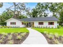 Charming single-story home featuring a yellow front door, red shutters, and well-manicured landscaping at 6921 N 16Th St, Tampa, FL 33610
