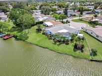 Waterfront home with screened pool, lush landscaping, well-maintained lawn and private dock on a sunny day at 9619 Towanda Ln, Port Richey, FL 34668