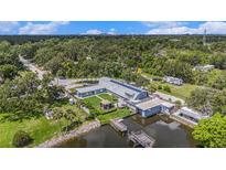 Waterfront home featuring a dock, lush landscaping, and unique architectural design with solar panels at 9938 Alavista Dr, Gibsonton, FL 33534