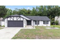 Charming home featuring black trim, a gray garage door, and a well-manicured front lawn at 15012 Winterwind Dr, Tampa, FL 33624