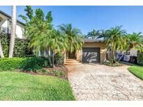 Charming single-story home featuring a tidy front yard with tropical landscaping and a patterned driveway at 200 Lamara Ne Way, St Petersburg, FL 33704