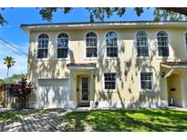 Charming two-story townhome with tan stucco, arched windows, and a one-car garage at 310 S Willow Ave # A, Tampa, FL 33606