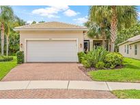 Charming single-story home featuring a brick driveway, two-car garage and tropical landscaping at 4911 Rock Island Ct, Wimauma, FL 33598