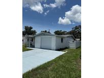 Single-story home with a white brick facade, attached garage, and a blue driveway at 5025 Tammy Ln, Holiday, FL 34690