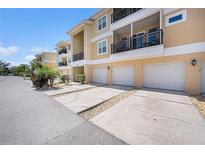Three-story condo building with attached garages, driveways, and balconies on a sunny day at 5065 Royal Palms Way # 303, New Port Richey, FL 34652