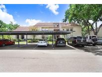 Exterior view of condo building with covered parking area and various parked cars on a bright sunny day at 5103 Puritan Cir # 5103, Tampa, FL 33617