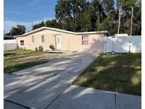 Charming pink brick home with a well-maintained lawn and a concrete driveway at 5601 Golden Dr, Tampa, FL 33634