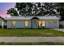 Charming single-story home featuring a white exterior, well-maintained lawn, and mature trees in background at 706 E Gate Dr, Safety Harbor, FL 34695