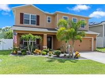 Two-story home featuring a manicured lawn, lush landscaping, and a welcoming front porch with seating at 8636 Prairie Creek Dr, New Port Richey, FL 34655