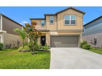Charming two-story home with a well-manicured lawn, an attached garage, and beautiful landscaping at 9815 Carabiner Way, Land O Lakes, FL 34637