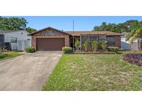 Charming brick home featuring a well-maintained lawn, mature landscaping, and an attached two-car garage at 105 Melrose Dr, Safety Harbor, FL 34695