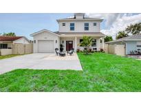 Charming two-story home with a manicured lawn and cozy outdoor seating area in front at 1410 Nebraska Ave, Palm Harbor, FL 34683