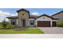 Beautiful single-story home with stone accents, a tile roof, three-car garage, and manicured landscaping at 14279 Swiss Bridge Dr, Riverview, FL 33579
