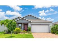 Charming single-Gathering home featuring a gray exterior, well-maintained landscaping, brick driveway and a two-car garage at 14424 59Th E Cir, Bradenton, FL 34211