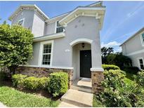 Inviting two-story home featuring a charming front entrance with stone accents and lush landscaping at 1878 Greenwood Valley Dr, Plant City, FL 33563