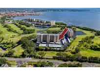 An aerial shot captures the condo building, nestled amidst lush greenery and a golf course near serene lake waters at 2621 Cove Cay Dr # 309, Clearwater, FL 33760