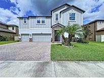 Charming two-story home with a brick driveway, lush lawn, and a beautiful palm tree accenting the front yard at 2798 Hilliard Dr, Wesley Chapel, FL 33543