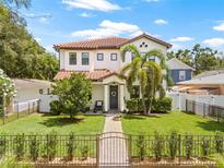 Charming two-story home features a red tile roof, lush landscaping, and an ornamental metal fence at 311 12Th N Ave, St Petersburg, FL 33701