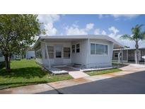 Well-maintained, bright one-story home with white exterior, a covered carport, and a grassy lawn at 3301 Alt 19 # 317, Palm Harbor, FL 34683