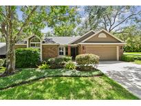 Charming single-story home with brick accents, mature trees, and well-maintained landscaping at 344 Cascade Ln, Palm Harbor, FL 34684