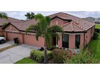Charming single-story home featuring a terracotta roof, mature landscaping and a two car garage at 5663 Sunset Falls Dr, Apollo Beach, FL 33572