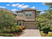 Inviting two-story home with a tile roof, brick driveway, and lush landscaping at 1391 Marinella Dr, Palm Harbor, FL 34683