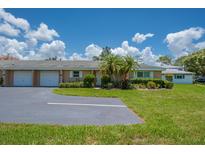 Charming villa featuring a well-manicured lawn, an attached garage and lush landscaping at 1510 Palmer Ct, Palm Harbor, FL 34685
