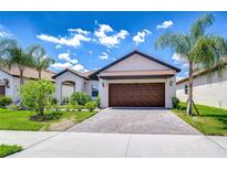 Charming single-story home with a tile roof, brick driveway, and well-maintained landscaping at 17140 Holly Well Ave, Wimauma, FL 33598