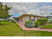 Charming single-story home featuring a well-maintained lawn, colorful flowers, and red shutters at 304 Fowling Ct # A, Sun City Center, FL 33573
