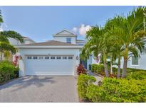 Charming two-story home with a brick driveway, a two-car garage and lush tropical landscaping at 314 Blackrock Ln, Apollo Beach, FL 33572