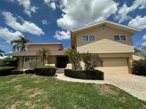Two-story home with a two-car garage, lush landscaping, and a winding walkway at 413 Midway Is, Clearwater Beach, FL 33767