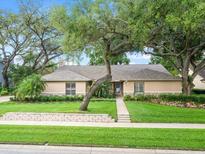 Charming single-story home featuring a well-manicured lawn and mature trees at 4610 Westford Cir, Tampa, FL 33618